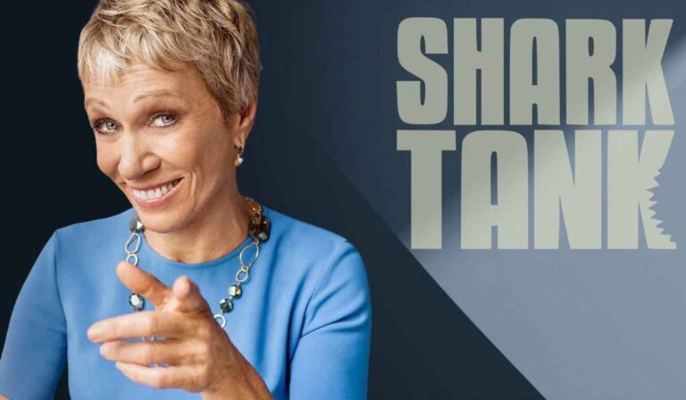 Woman in a blue dress smiling and pointing in front of the Shark Tank logo