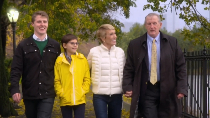 Barbara Corcoran walks with her family in a park, smiling and holding hands with her husband
