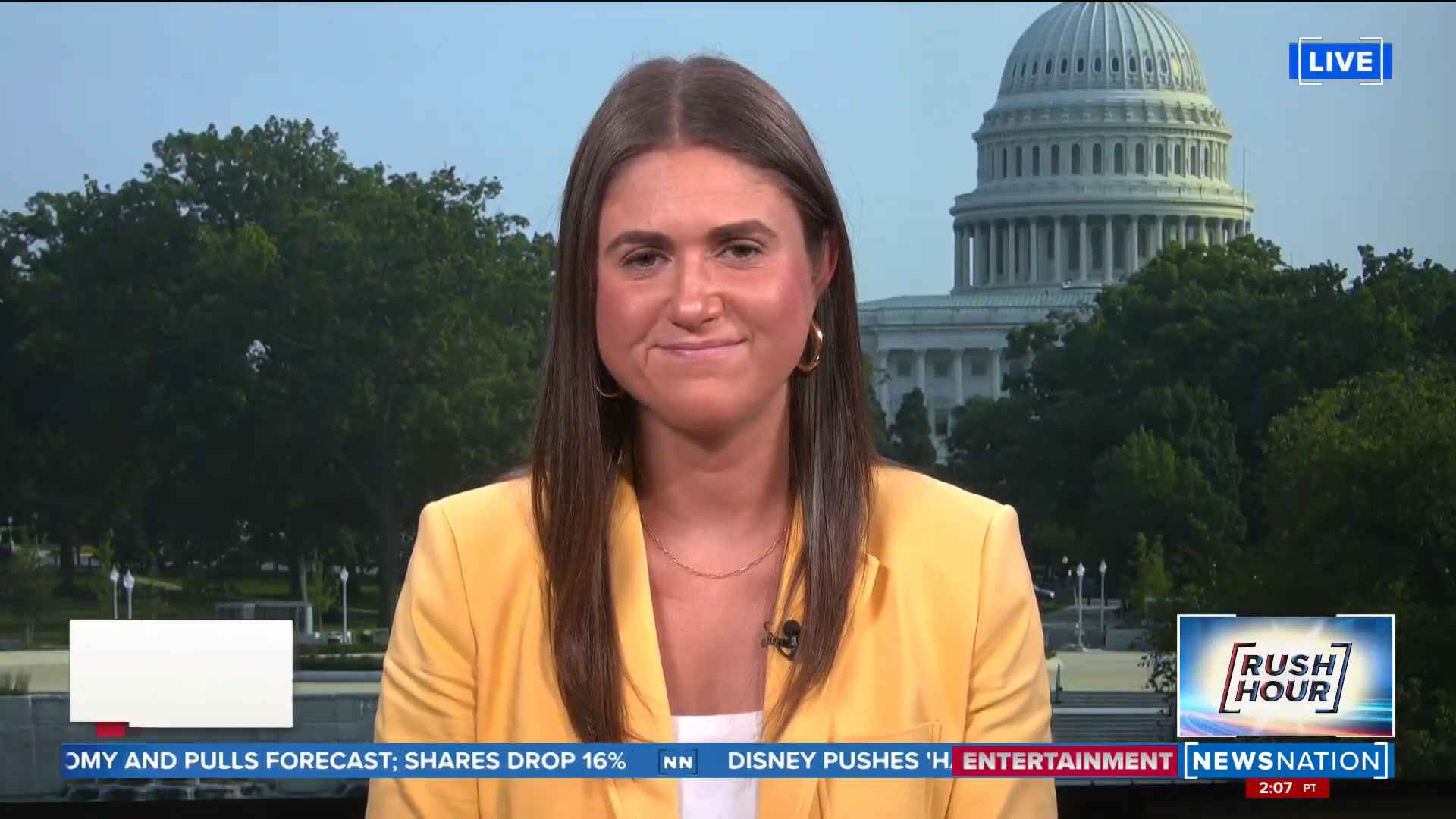 Female news reporter in a yellow blazer broadcasting live with the U.S. Capitol in the background