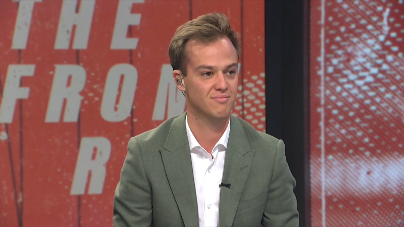 Guy Heveldt sits in front of a red and white background