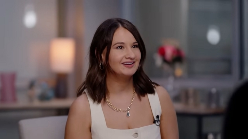 Gypsy Rose Blanchard speaking during an interview, wearing a white outfit and gold jewelry