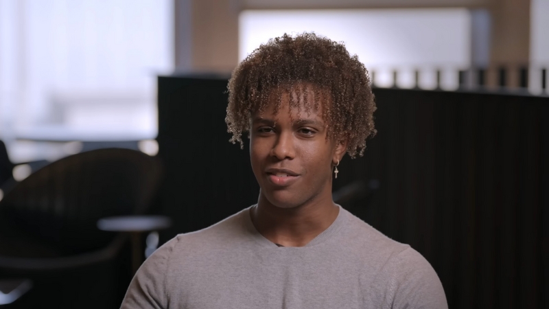 Nathaneo Johnson wearing a gray shirt sits for an interview in a modern setting