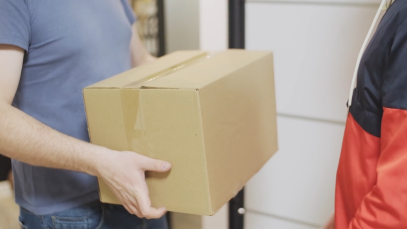 A person hands over a sealed cardboard box during delivery