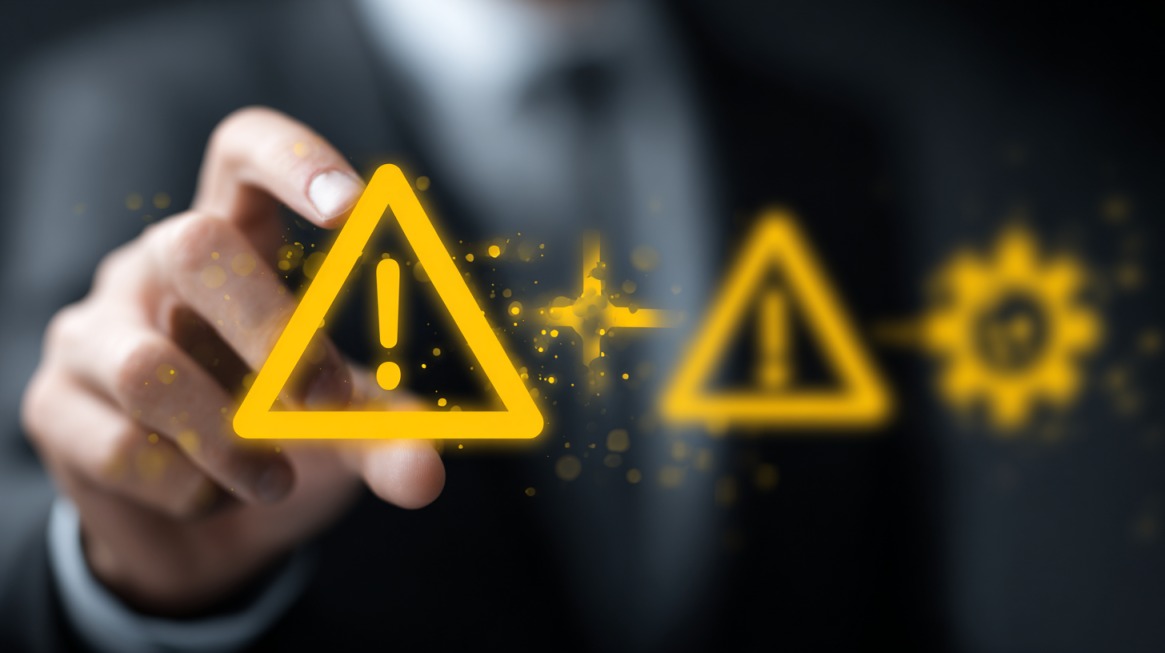 Hand pointing to a glowing warning triangle icon on a digital interface