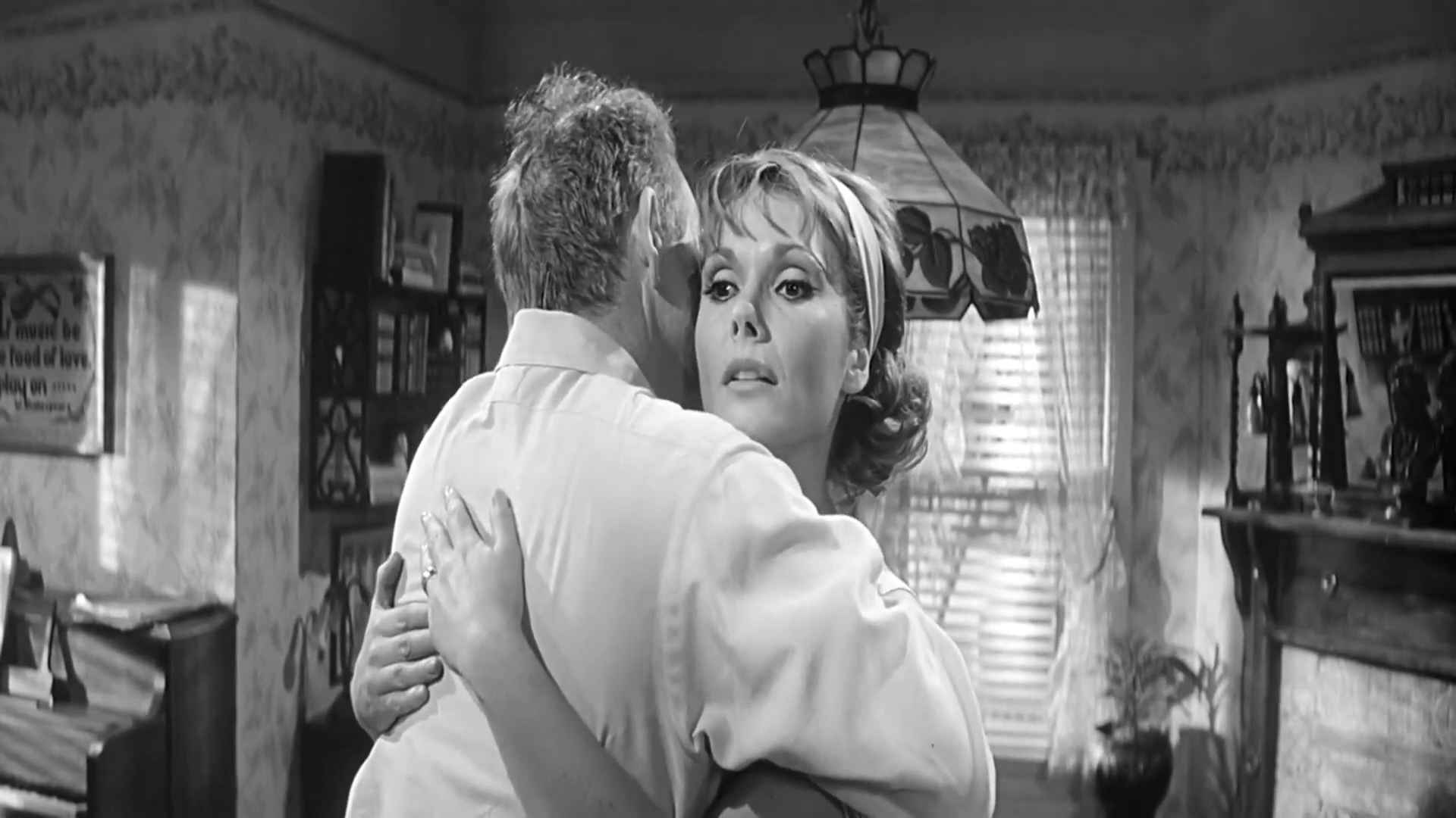 Black and white film scene showing Felicia Farr embracing Jack Lemmon indoors