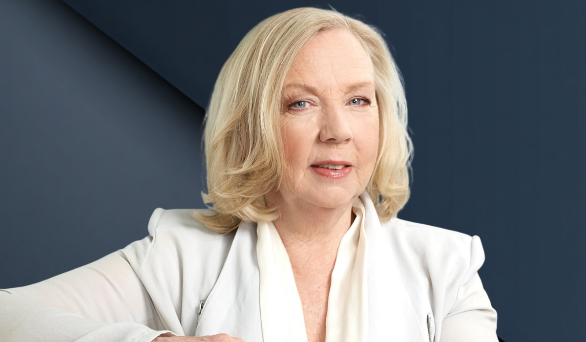 A professional portrait of Deborah Meaden sitting in a dark leather chair with her hands clasped, appearing thoughtful and attentive