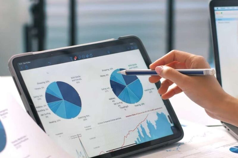 Hand pointing at pie charts and analytics dashboards on a tablet during data strategy planning