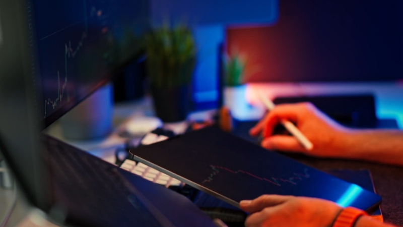 Hands using a tablet to check financial charts at a desk