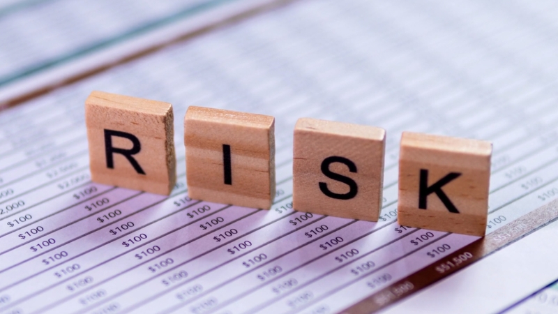 Wooden blocks spelling “RISK” placed on top of a financial spreadsheet