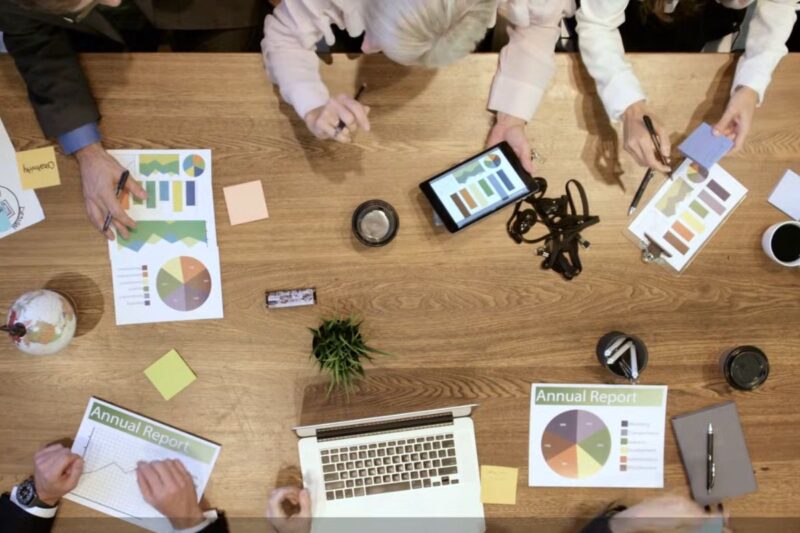 Top view of a team reviewing charts and reports around a table, illustrating shared responsibility in data strategy