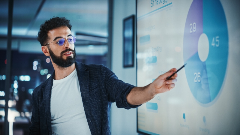 Marketing professional presenting analytics data and growth metrics on a digital screen