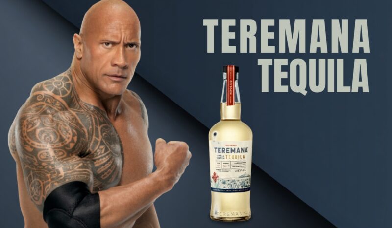 Muscular tattooed man posing next to a bottle of Teremana Tequila