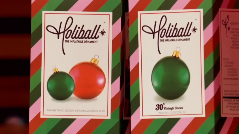 Boxed Holiball inflatable Christmas ornaments in red and green retail packaging displayed on a store shelf