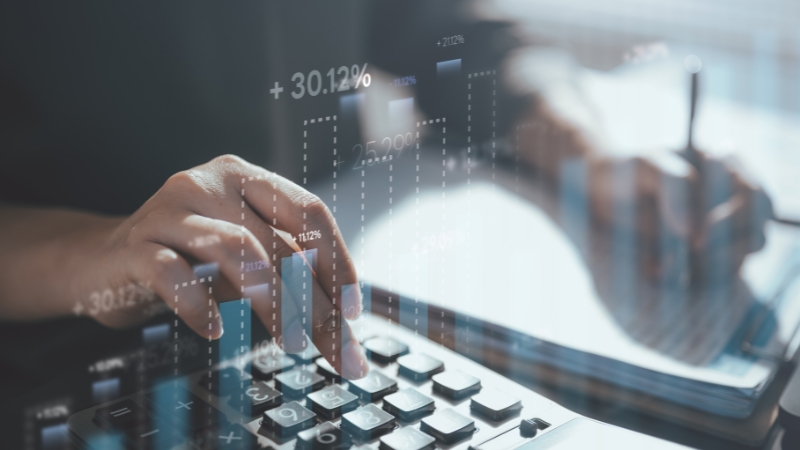 Person analyzing financial data on a tablet and calculator with performance charts overlay