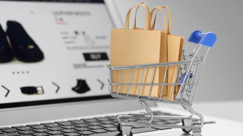 Shopping cart with paper bags in front of an online store on a laptop screen