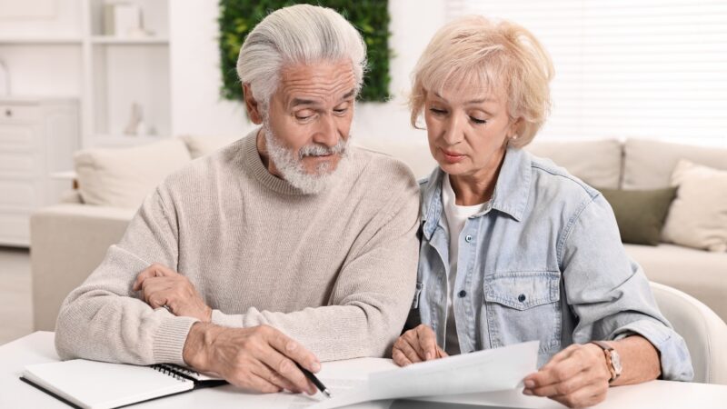An older couple reviews debt paperwork together at home