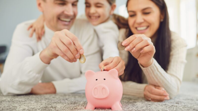 A family adds coins to a piggy bank for future savings goals