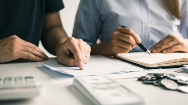 Parents compare household bills and notes while setting financial priorities for a family budget