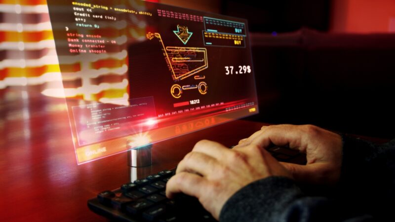 Hands enter data beside a hacked online payment screen