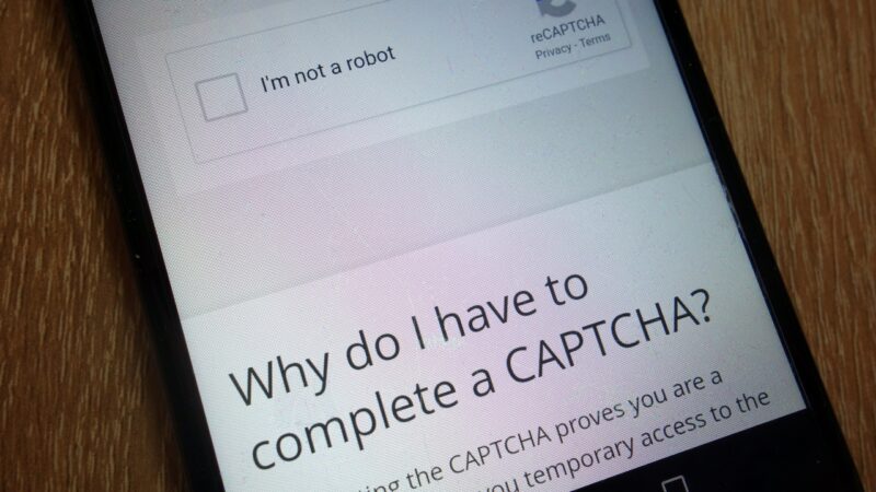 A phone screen displays a CAPTCHA prompt for bot protection