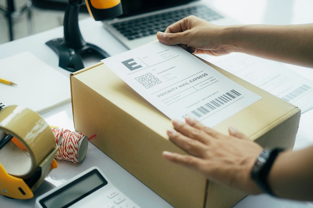 Young business owner putting shipping label on parcel